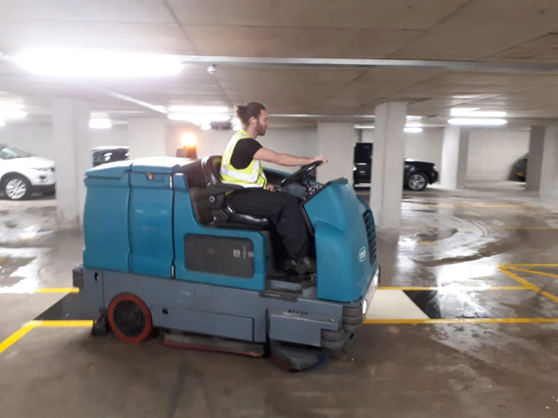 Autolaveuse industrielle en action dans un parking souterrain avec opérateur professionnel